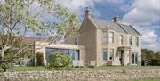 The exterior of Merryfields, a large modern cottage with a low stone wall in front.