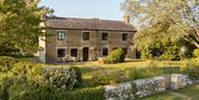 The exterior of Park Farm Cottage, a large cottage with spacious garden and stone wall.