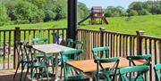 Outside table and chairs with a view of grass and a kids play area