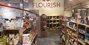 Inside of a farm shop with shelves of nice tinned/jarred products and a sign in the background that says 'Flourish'