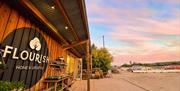 The outside of Flourish home and lifestyle shop timber building with a pink sky and car park in background