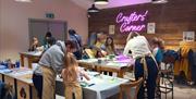 Crafters standing around tables making pots in Crafters Corner.