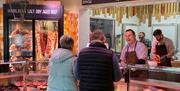 Two people buying meat from a butchers counter in the farm shop