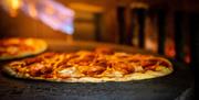 A pepperoni pizza being cooked inside a pizza oven