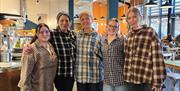 Five people linking arms in a row inside a large cafe.