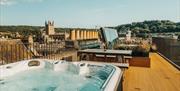 A hot tub and picnic bench on a rooftop terrace, with Bath Abbey visible in the background.