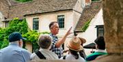 Tour guide sharing their knowledge with the group in a village in the Cotswolds