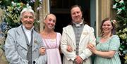 Four staff members dressed in regency clothing stand outside the entrance to the Jane Austen Centre.