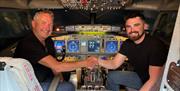 Two men sat inside a jet flight simulator