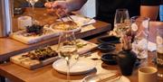 A table full of sushi plates being enjoyed with wine and chopsticks.