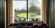 View of the back of a double bed out to the grounds through double glass french doors.