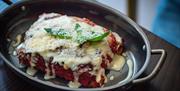 A lasagne with white sauce on a black dish.