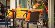 Outdoor seating area at Osteria Partenopea, with chairs holding yellow and orange cushions.