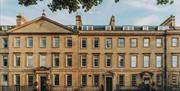 A view of the outside of the hotel in a row of grand sandstone Georgian buildings.