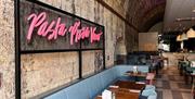 Pink signage alongside the dining area at Prezzo Bath reads "Pasta Pizza Vino"