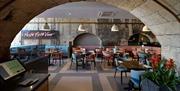 The interior dining area at Prezzo Bath, with arched stone ceiling and exposed brick walls.