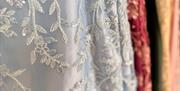 Close up of a pale blue dress with intricate white beaded floral designs.
