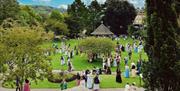 Wide shot of a park full of people dressed in regency costumes.