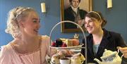 Two women having afternoon tea while dressed in period costume at the Regency Tea Room inside The Jane Austen Centre in Bath.