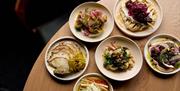 Six plates of food on a round table