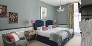 A Georgian style bedroom with grey blue tones and two dark blue single beds.