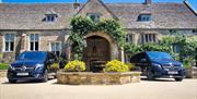 Two black Mercedes vehicles parked in front of the entrance to Coombe End Manor