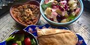 Colourful Persian-inspired bowls and plates of food decorated with flowers.