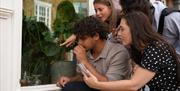 Four people crouched around a storefront window looking at the contents of the window sill.