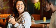 A woman laughs while holding a briefcase, looking at a man beside her.