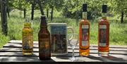 Bottles of assorted alcoholic drinks from Burrow Hill Cider lined up on a wooden bench.