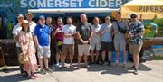 Tour group stood in front of a bus with "Somerset Cider" written on the side.