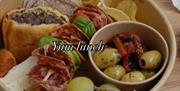 A deli-style lunch spread with cold cut meats, grapes, olives, sausage rolls and cheese. The words "Yum lunch" are pasted in the middle of the image.
