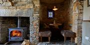 A brick room with a black fire place and bench seating in the right corner