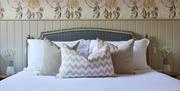 A large bed with white sheets and various pillows in different colours and sizes