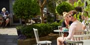 A group of people sat in an outdoor area that is full of greenery