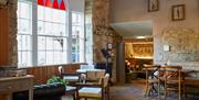 A room with white walls and exposed bricks, wooden floors, and wooden tables and chairs
