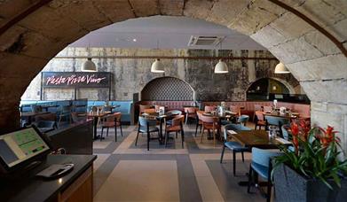 The interior dining area at Prezzo Bath, with arched stone ceiling and exposed brick walls.