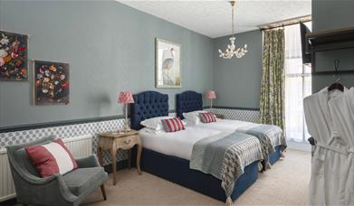 A Georgian style bedroom with grey blue tones and two dark blue single beds.