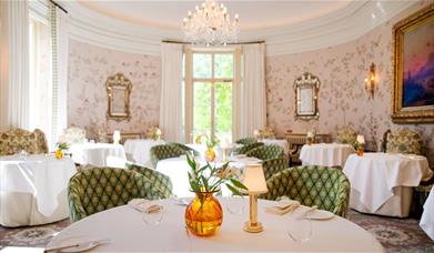 Rows of elegant white tables with green chairs at Restaurant Hywel Jones