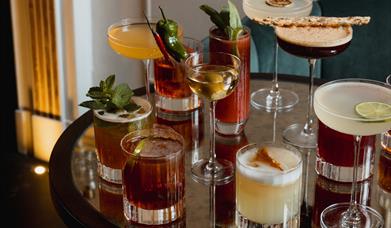 A collection of cocktails on a table in the bar area of No.15 by GuestHouse Bath.